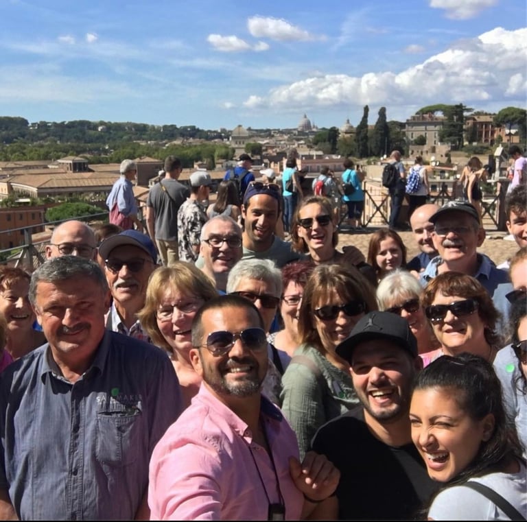 Crowd of tourists at a historic Roman ruins site with ancient structures and green landscape visible in background